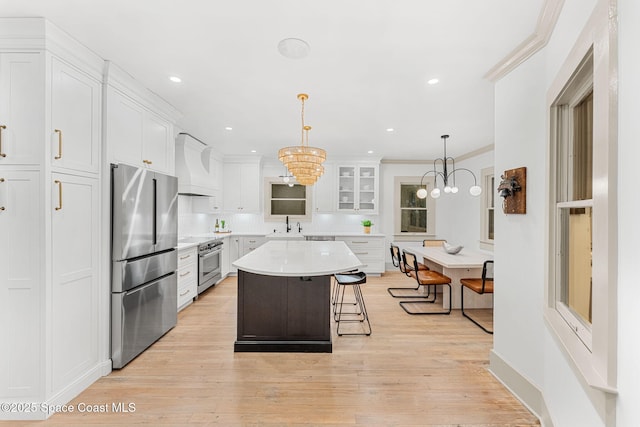 kitchen with premium range hood, stainless steel appliances, a center island, a kitchen breakfast bar, and white cabinets