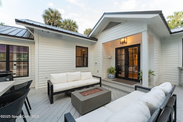 wooden deck with an outdoor living space with a fire pit and french doors