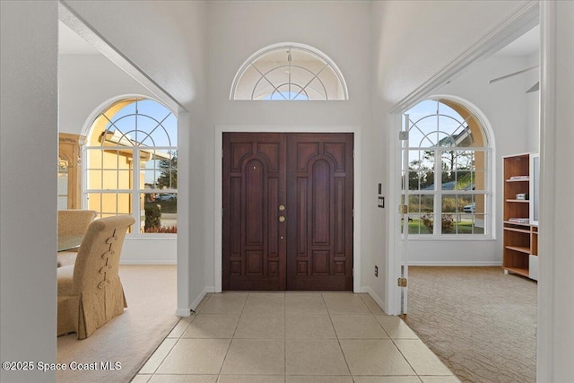 entrance foyer featuring a towering ceiling and light colored carpet