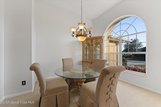 carpeted dining area featuring lofted ceiling and a chandelier