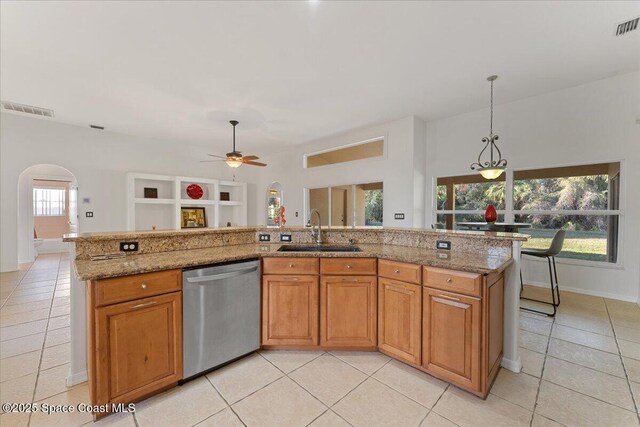 kitchen featuring sink, hanging light fixtures, a center island with sink, dishwasher, and light stone countertops