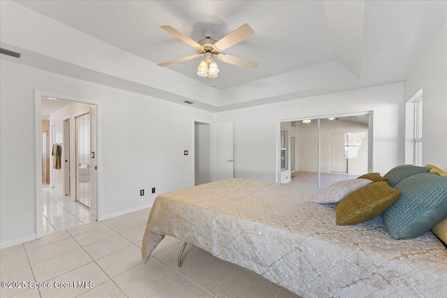 bedroom featuring light tile patterned flooring, ceiling fan, and a tray ceiling