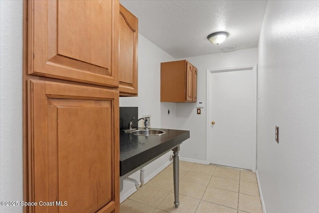 kitchen featuring sink, a textured ceiling, and light tile patterned floors