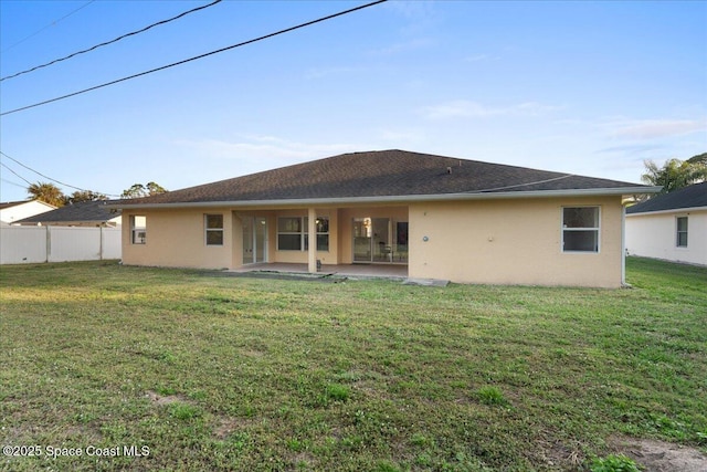 rear view of house featuring a lawn and a patio