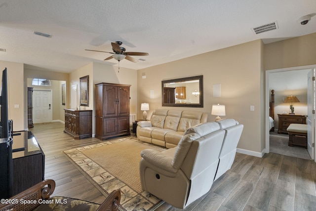 living room with hardwood / wood-style flooring, a textured ceiling, and ceiling fan