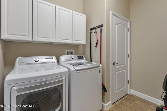 clothes washing area with light tile patterned floors, cabinets, and washer and dryer