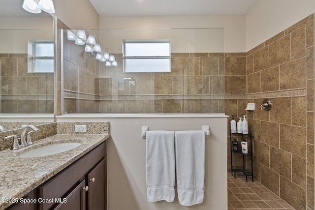 bathroom with tiled shower and vanity