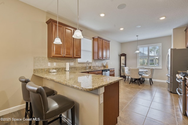 kitchen featuring light stone countertops, tasteful backsplash, a kitchen breakfast bar, kitchen peninsula, and pendant lighting