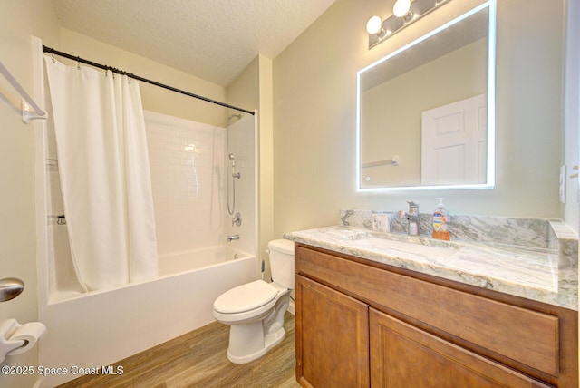 full bathroom with a textured ceiling, wood-type flooring, vanity, toilet, and shower / bath combo with shower curtain