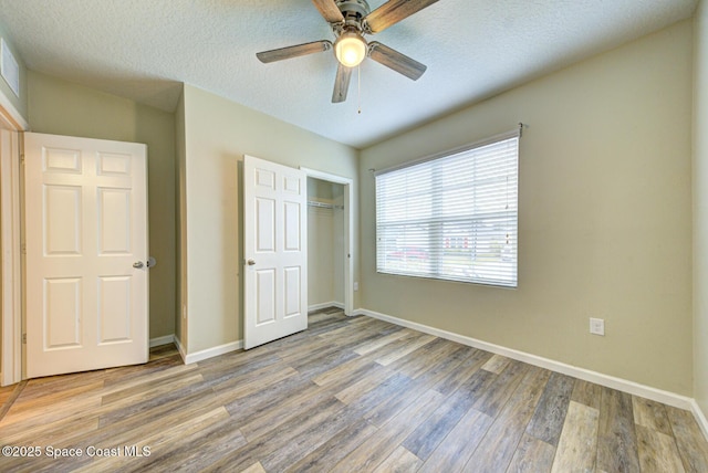 unfurnished bedroom with a closet, ceiling fan, hardwood / wood-style floors, and a textured ceiling