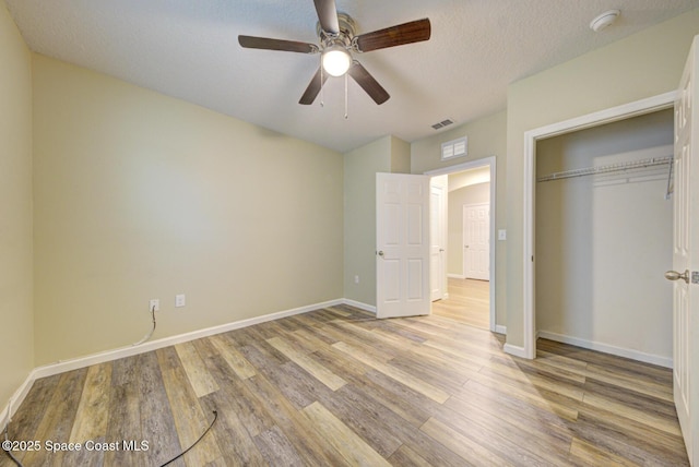 unfurnished bedroom featuring a closet, ceiling fan, light wood-type flooring, and a textured ceiling