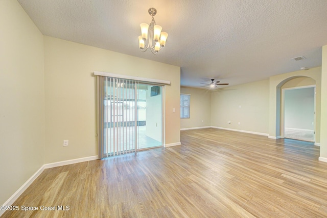 spare room featuring ceiling fan with notable chandelier, light hardwood / wood-style flooring, and a textured ceiling