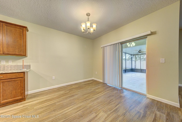 unfurnished dining area with a textured ceiling, light hardwood / wood-style flooring, and a chandelier