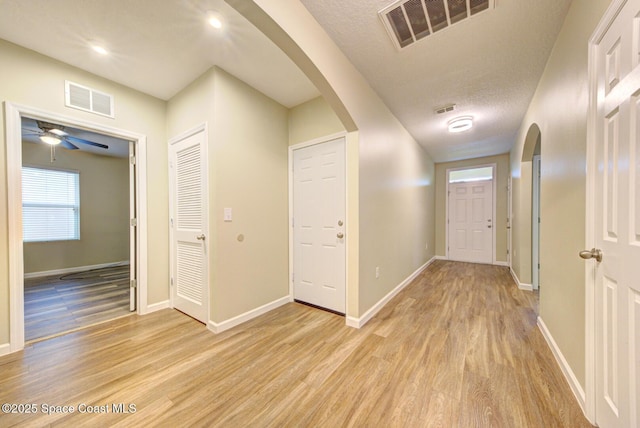 hallway with light wood-type flooring and a textured ceiling