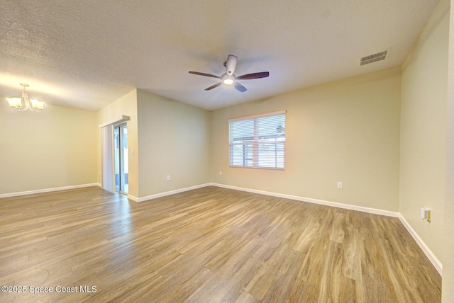 spare room with ceiling fan with notable chandelier, light hardwood / wood-style floors, and a textured ceiling