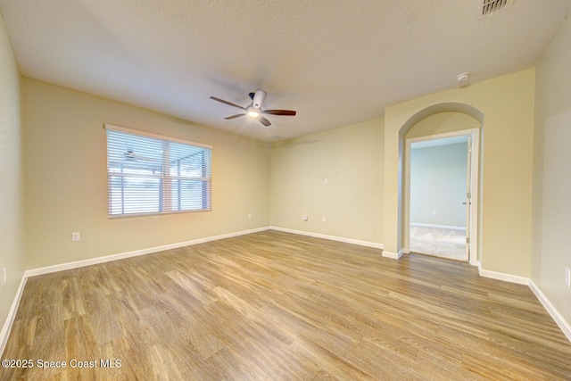 spare room featuring light wood-type flooring, a textured ceiling, and ceiling fan