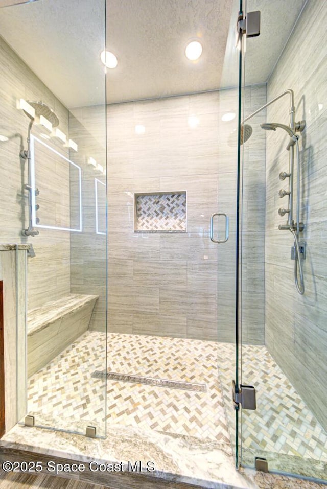 bathroom with a shower with shower door and a textured ceiling