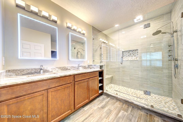 bathroom with hardwood / wood-style floors, a textured ceiling, walk in shower, and vanity