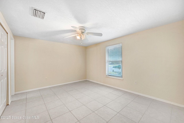 empty room with light tile patterned floors, baseboards, visible vents, ceiling fan, and a textured ceiling