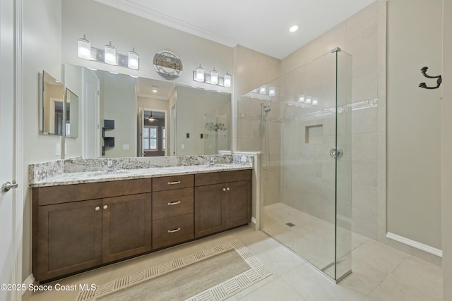 bathroom featuring a tile shower, vanity, ornamental molding, and tile patterned floors