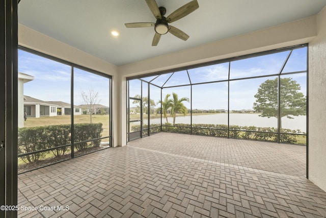 unfurnished sunroom with ceiling fan and a water view