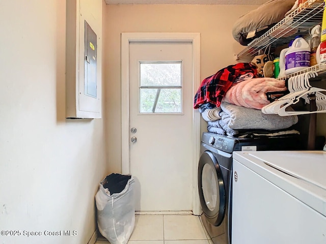 laundry room with light tile patterned flooring, electric panel, and washer and clothes dryer