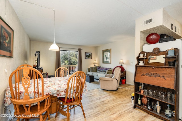 dining space featuring light hardwood / wood-style floors and a textured ceiling