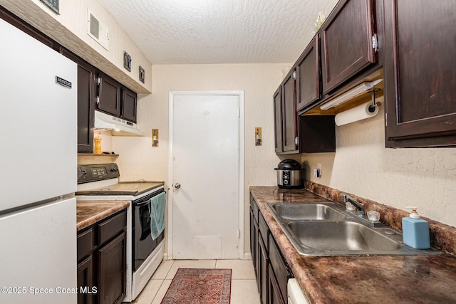 kitchen with sink, light tile patterned floors, white appliances, dark brown cabinetry, and a textured ceiling