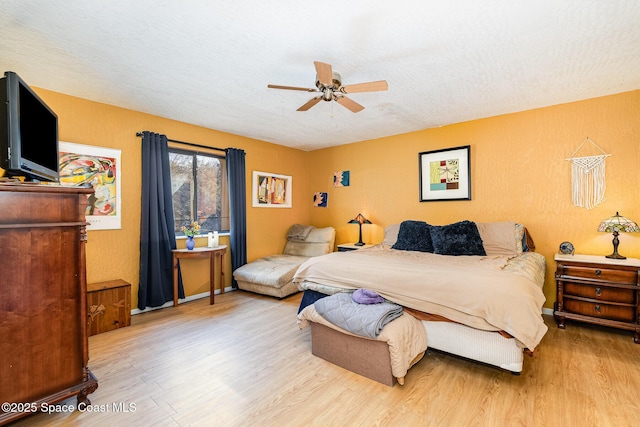 bedroom featuring ceiling fan, hardwood / wood-style floors, and a textured ceiling