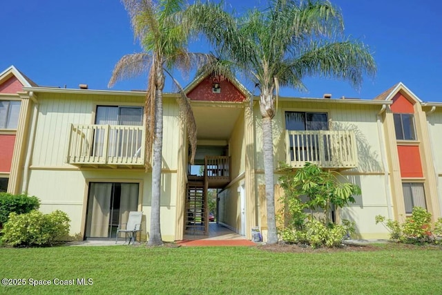 rear view of property featuring a balcony and a yard