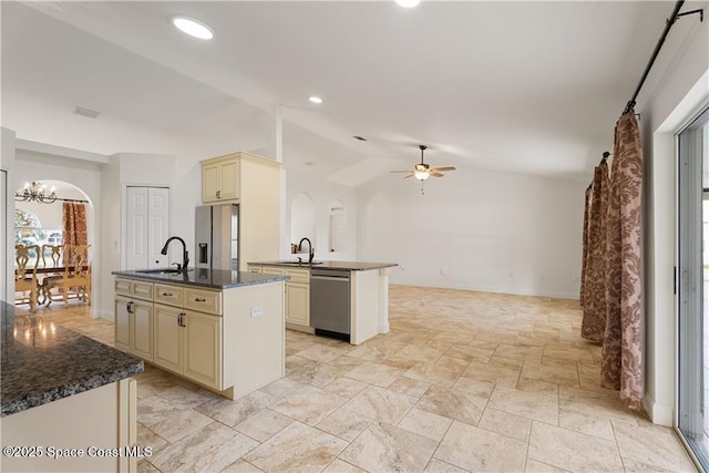 kitchen with stainless steel appliances, lofted ceiling, a kitchen island with sink, and cream cabinets