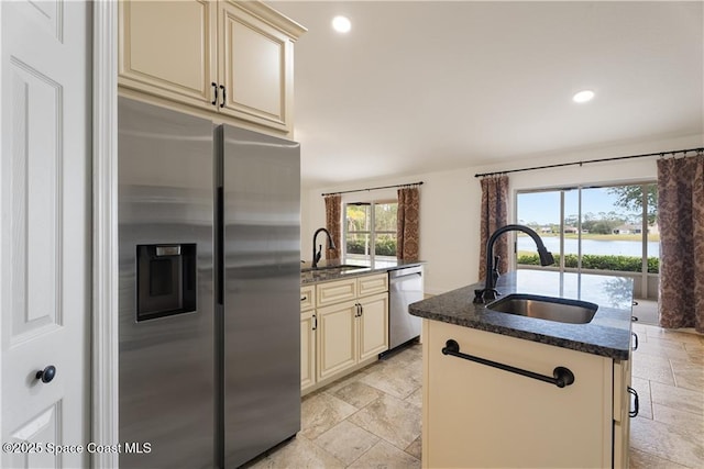 kitchen with stainless steel appliances, sink, dark stone counters, and cream cabinetry