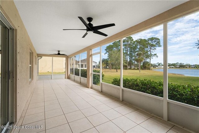 unfurnished sunroom featuring a water view and ceiling fan