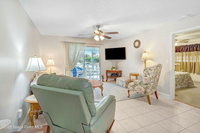 living room featuring light tile patterned floors, a textured ceiling, and ceiling fan