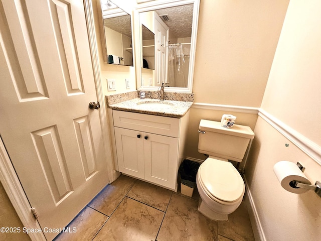 bathroom with vanity, a textured ceiling, tile patterned floors, and toilet