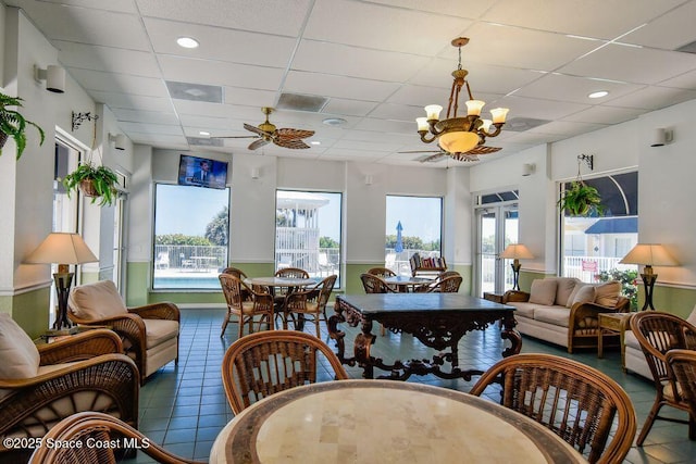 interior space with ceiling fan with notable chandelier and a paneled ceiling