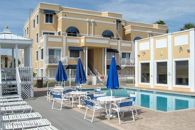 rear view of house with a community pool and a patio area