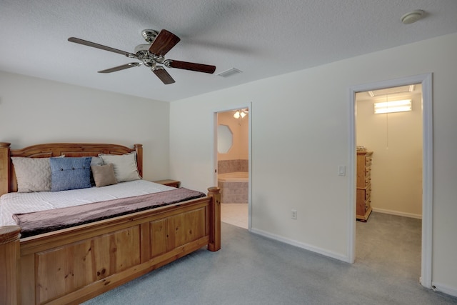 bedroom featuring light colored carpet, a textured ceiling, ceiling fan, and ensuite bath