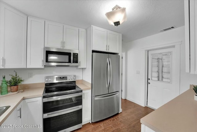 kitchen with stainless steel appliances, dark hardwood / wood-style flooring, a textured ceiling, and white cabinets