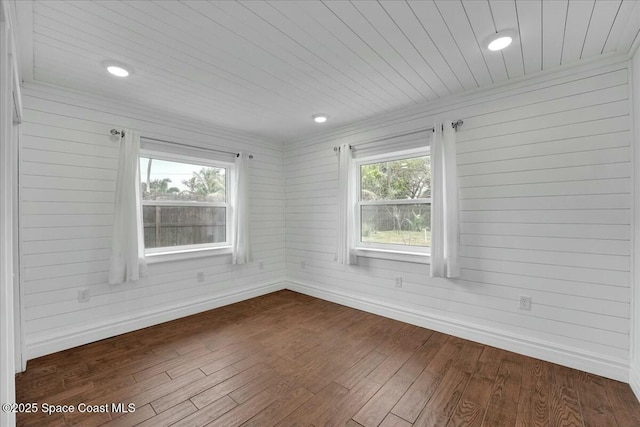 empty room with dark wood-type flooring, wood ceiling, and wood walls