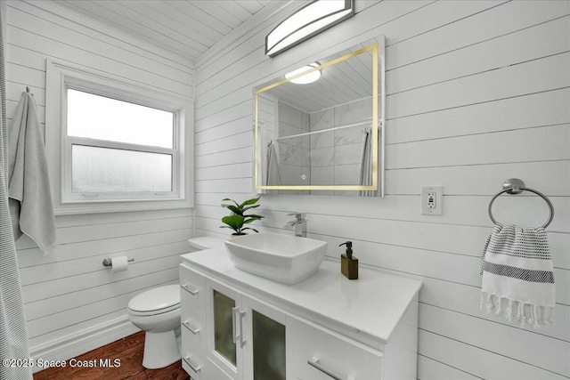 bathroom with wood walls, wood-type flooring, vanity, toilet, and a shower with shower curtain