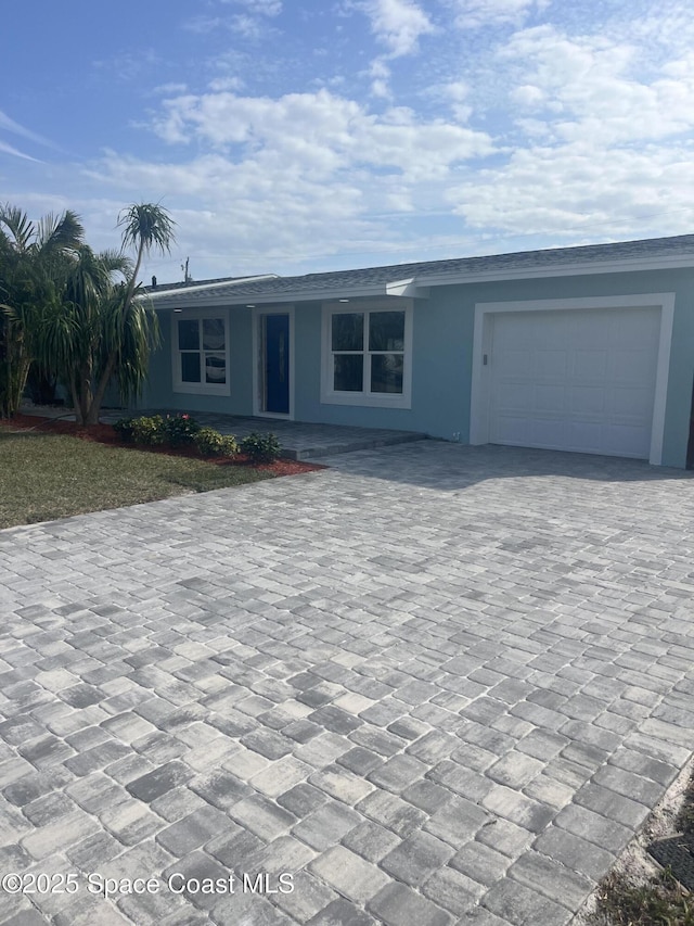 view of front of home with decorative driveway, a garage, and stucco siding