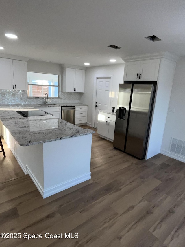 kitchen featuring visible vents, a sink, backsplash, stainless steel appliances, and white cabinets