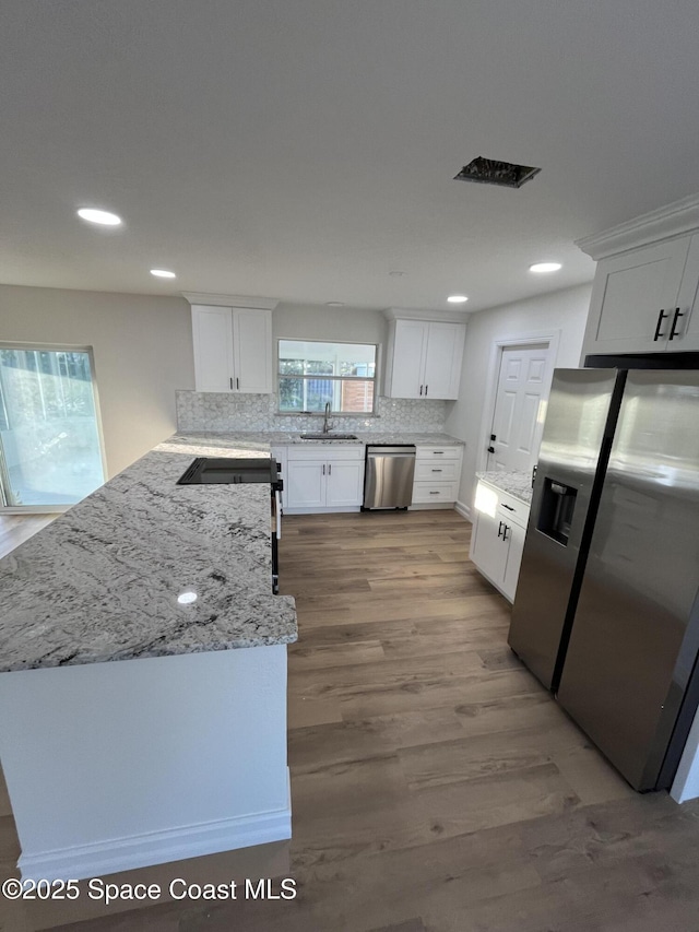 kitchen featuring sink, tasteful backsplash, appliances with stainless steel finishes, light hardwood / wood-style floors, and white cabinets