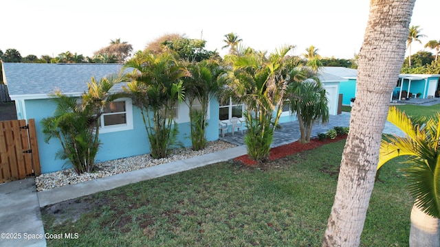 view of side of property with stucco siding, a shingled roof, and a yard