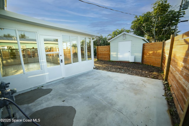 view of patio with an outdoor structure, a fenced backyard, and a shed