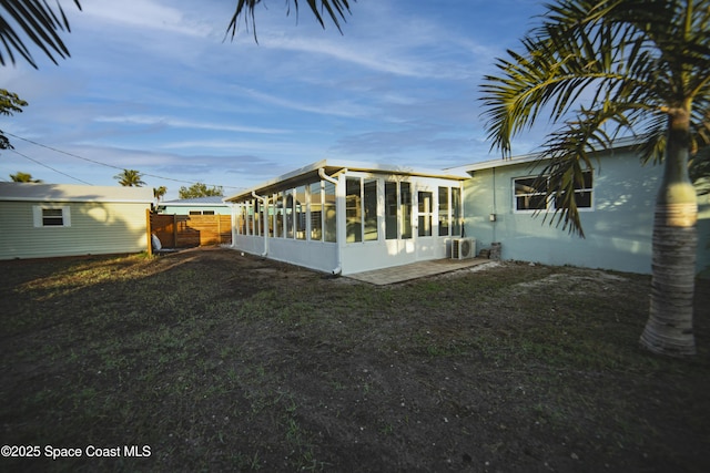 view of side of property with ac unit, fence, and a sunroom