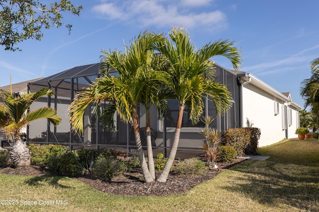 view of side of property featuring a lanai, stucco siding, and a lawn