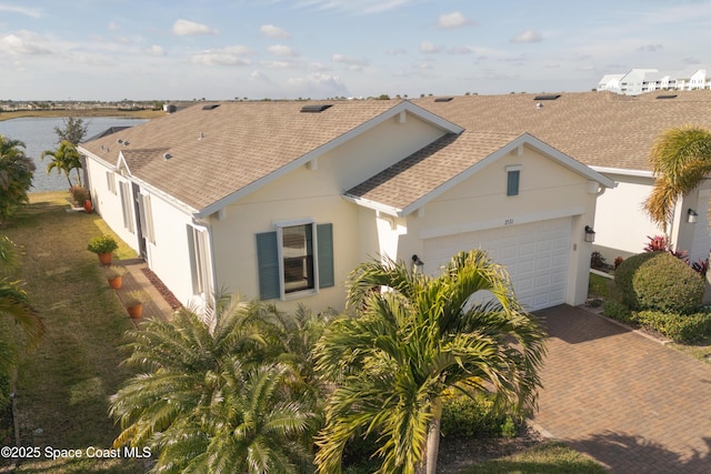 view of front of property featuring a shingled roof, a garage, stucco siding, and decorative driveway