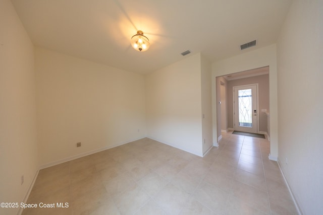 unfurnished room featuring light tile patterned floors, visible vents, and baseboards